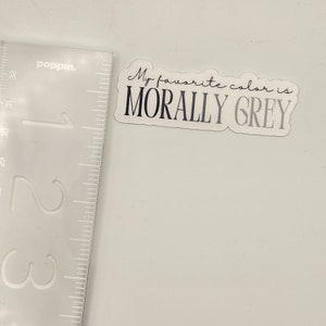 May include: A white sticker with rounded corners and a black outline. The sticker says "My favorite color is MORALLY GREY" in a handwritten font.
