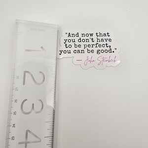 May include: A white sticker with a quote by John Steinbeck: "And now that you don't have to be perfect, you can be good."