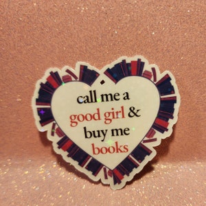 May include: A white heart-shaped sticker with a red and black border. The sticker has the text "call me a good girl & buy me books" on it.