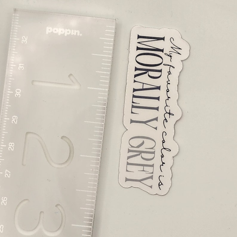May include: A white sticker with black text that reads "My favorite color is MORALLY GREY".