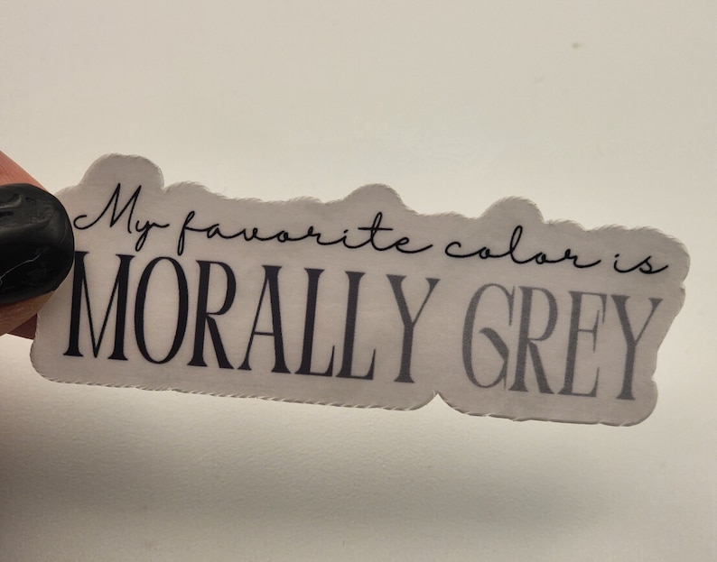 May include: White sticker with black text that reads "My favorite color is MORALLY GREY".