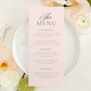 May include: A pink menu card with a gold-rimmed plate and floral decorations. The menu card lists the starter, entree, and dessert options. The starter is chickpea tahini, lemon, red pepper hummus & oven baked pita. The entree is baked chicken with tomato, arugula, a truffle vinaigrette. The dessert is caramelized banana split with vanilla ice cream, whipped cream and caramel sauce.