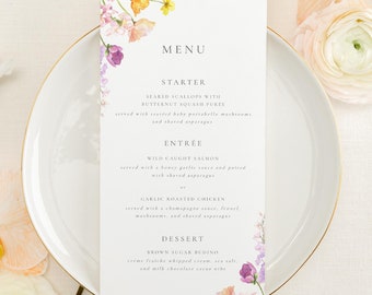 Op de afbeelding: Een menukaart met een bloemenmotief, met een witte achtergrond en een aquarelillustratie van bloemen en groen. Het menu bevat de volgende items: Voorgerecht: Gebakken Sint-jakobsschelpen met pompoensoep, Hoofdgerecht: Wilde zalm of knoflookkip, Nagerecht: Brown Sugar Budino.