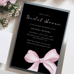May include: Black and white bridal shower invitation with a pink bow. The invitation reads "Join us for a Bridal Shower as we honor the bride-to-be Amanda Murphy. Saturday, July 15th, 2 PM. The Rose Cafe, 888 Love Lane, Los Angeles, CA. RSVP to Amanda 444-444-4444. Registered at prettyregistry.com"