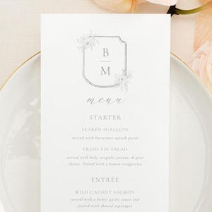 May include: A white wedding menu card with a floral design and the initials "B" and "M" in a frame. The menu includes starter, entree, and dessert options.