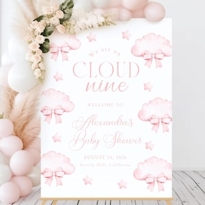 May include: A pink and white baby shower welcome sign with the text "We are on CLOUD nine" and "Welcome to Alexandra's Baby Shower". The sign features pink watercolor clouds with bows and stars.
