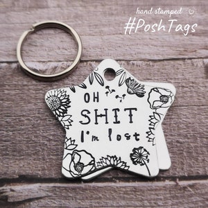 May include: A silver star-shaped dog tag with a black floral design and the text "OH SHIT I'm lost".