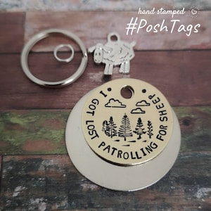 Puede incluir: Un llavero de metal dorado con una etiqueta redonda que dice "I got lost patrolling for sheep" con una pequeña silueta de oveja y un anillo de llave.