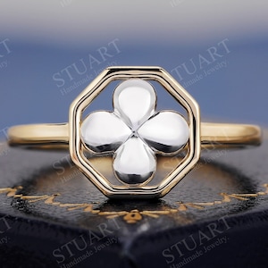 Puede incluir: Un anillo de oro y plata con un diseño de trébol de cuatro hojas. El trébol está engastado en un marco octogonal.