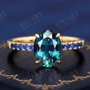 Pu&ograve; includere: Un anello d'oro con una grande pietra ovale di colore turchese circondata da una fila di piccole pietre blu.