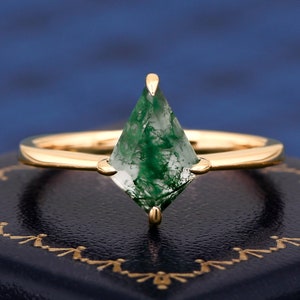 Op de afbeelding: Een gouden ring met een groene mosagaat edelsteen in een vlieger vorm.