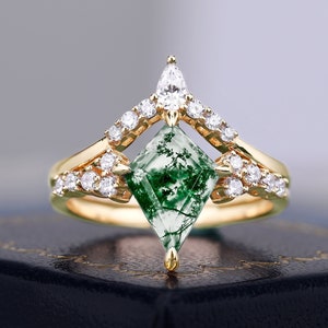 Puede incluir: Un anillo de oro con una piedra preciosa de ágata verde musgo engastada en forma cuadrada. El anillo está adornado con pequeños diamantes y tiene un diseño puntiagudo.