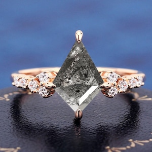 May include: A rose gold engagement ring with a large, dark gray, kite-shaped diamond and smaller diamonds set in the band.