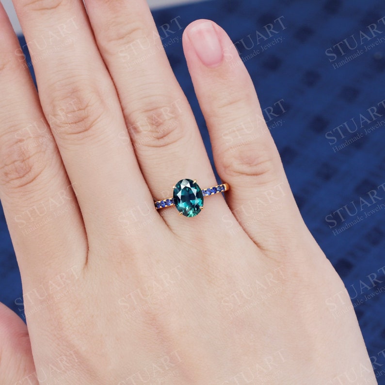 Pu&ograve; includere: Un anello d'oro con una pietra preziosa verde ovale circondata da piccole pietre blu.