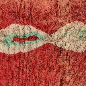Puede incluir: Una alfombra roja y blanca con un dise&ntilde;o verde. La alfombra tiene una textura suave y est&aacute; hecha de lana.