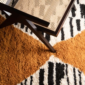 May include: A black wooden chair with a woven cane seat sits on a rug with a black and white striped pattern and a brown, fluffy section.