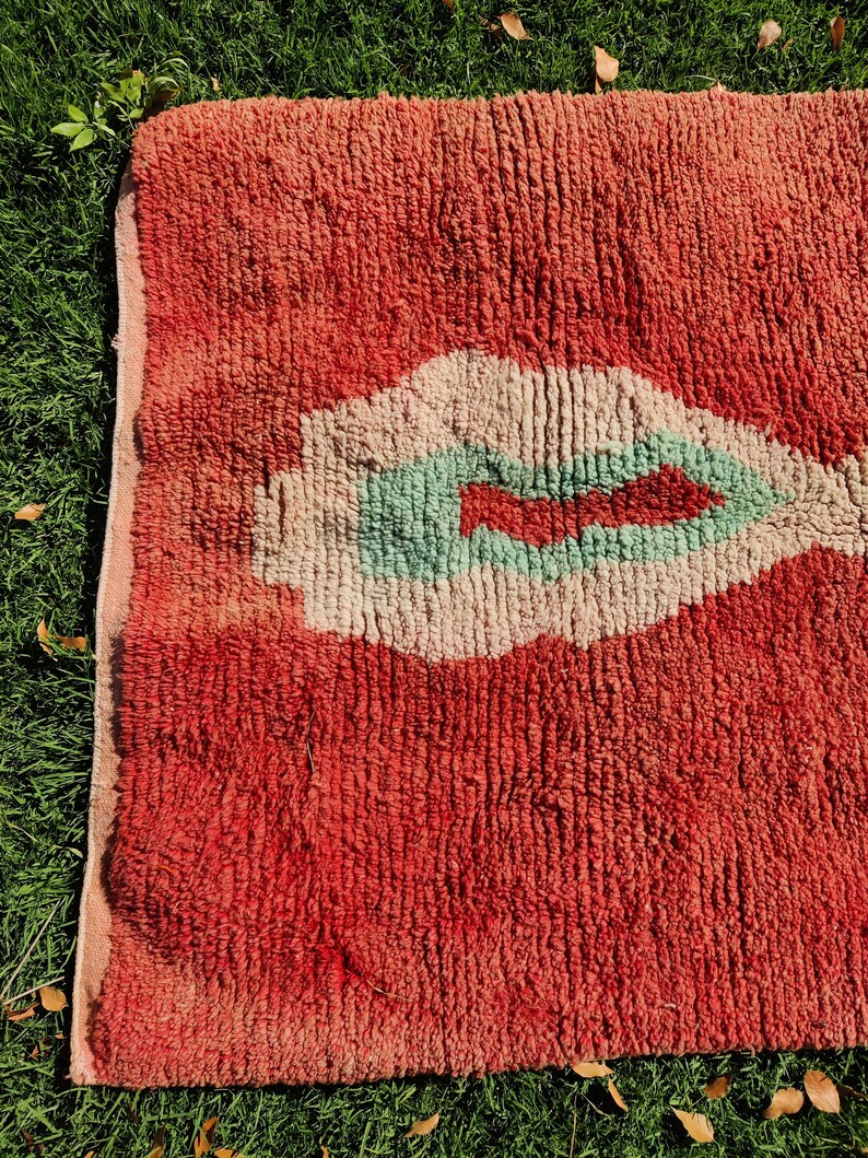Puede incluir: Una alfombra roja, blanca y verde con un dise&ntilde;o abstracto &uacute;nico. La alfombra tiene una superficie texturizada y esponjosa.