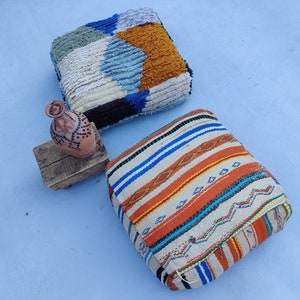 K&ouml;nnte beinhalten: Zwei bunte, gemusterte Bodenkissen, eines mit einem geometrischen Muster in Blau, Wei&szlig; und Orange, das andere mit einem Streifenmuster in Orange, Blau und Wei&szlig;.