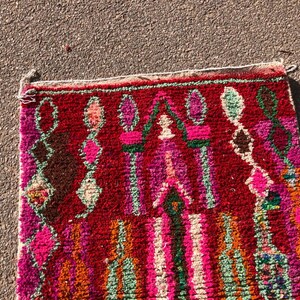 Puede incluir: Una alfombra marroqu&iacute; colorida con fondo rojo y intrincados patrones geom&eacute;tricos en tonos de rosa, verde y naranja.