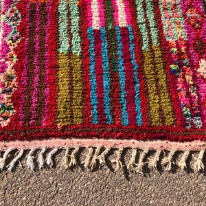 Puede incluir: Una alfombra de rayas coloridas con un borde de flecos. La alfombra est&aacute; hecha de lana y tiene una variedad de colores, incluyendo rosa, rojo, verde, azul y marr&oacute;n.