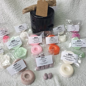 Könnte beinhalten: Sortiment an Wachsschmelzen in verschiedenen Düften und Formen, verpackt in durchsichtigen Plastiktüten mit Etiketten. Die Wachsschmelzen haben die Form von Kreisen, Sechsecken und Herzen. Zu den Düften gehören Lavendel, Tee & Bergamotte, Orange & Basilikum und mehr.