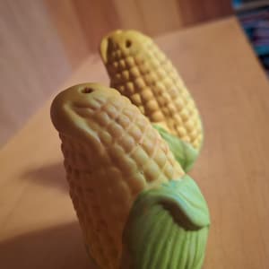 May include: Two ceramic corn on the cob salt and pepper shakers. The shakers are yellow with green husks.