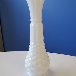 May include: A white milk glass vase with a woven pattern and a fluted top.