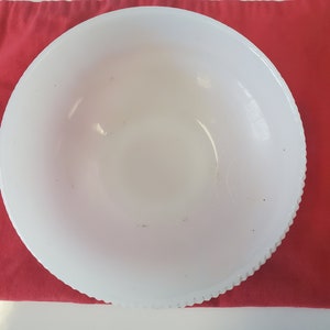 May include: A white ceramic bowl with a scalloped edge. The bowl is empty and has a few small brown spots on the inside.