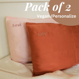 Puede incluir: Dos fundas de almohada personalizadas, una rosa con el nombre "Sarah" bordado y una naranja con el nombre "Lily" bordado. Las fundas de almohada est&aacute;n hechas de seda vegana y son parte de un paquete de dos.