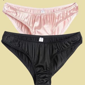 May include: Two pairs of underwear, one black and one pink, made of satin fabric. Both pairs have a low rise and a smooth, silky texture.