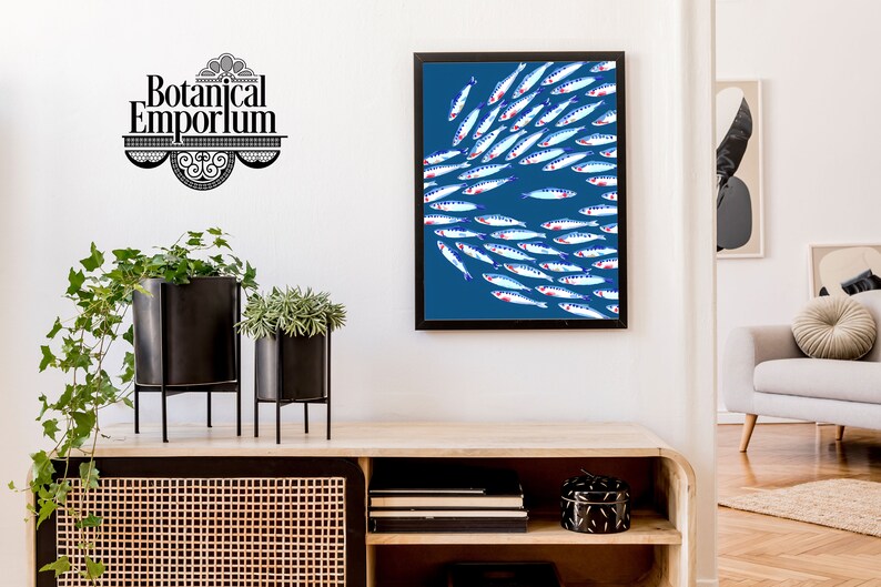 Puede incluir: Una impresi&oacute;n enmarcada de un banco de peces nadando en un fondo azul. Los peces son blancos con acentos azules y rojos. La impresi&oacute;n est&aacute; colgada en una pared blanca sobre un estante de madera.