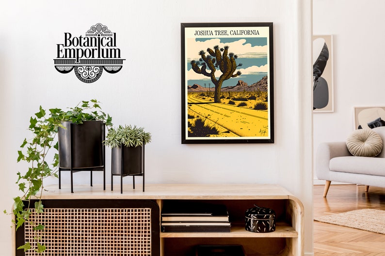 May include: A framed poster with a vintage illustration of a Joshua Tree in the desert. The poster is titled "Joshua Tree, California". The poster is hanging on a white wall above a wooden shelf with black metal plant stands and potted plants.