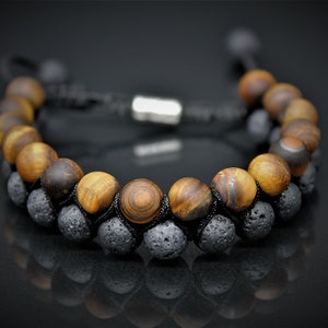 May include: A black cord bracelet with brown and black tiger's eye beads and black lava rock beads.