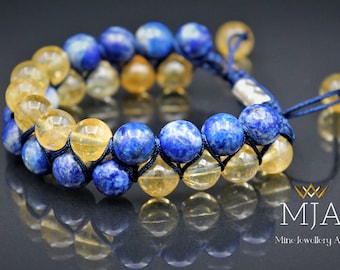Könnte beinhalten: Ein Armband mit abwechselnden Reihen aus blauen und gelben Edelsteinen. Die blauen Steine haben ein gesprenkeltes Aussehen, während die gelben Steine durchscheinend sind. Das Armband ist auf einer dunkelblauen Kordel aufgezogen.