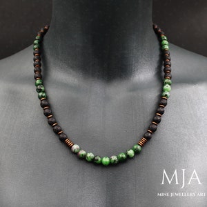 May include: A necklace with green and black beads. The beads are strung on a copper wire. The necklace is on a mannequin's neck. The text "MJA MINE JEWELLERY ART" is at the bottom of the image.