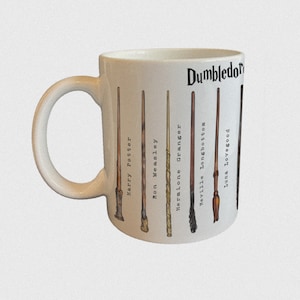 Puede incluir: Taza de cerámica blanca con ilustraciones de varitas de la serie Harry Potter. Las varitas están etiquetadas con nombres de personajes como Harry Potter y Hermione Granger. La palabra "Dumbledore" está impresa en la parte superior.