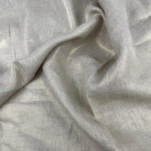 以下が含まれることがあります： ベージュ色の生地のクローズアップ。 わずかな光沢があります。 素材は軽くテクスチャ加工されており、柔らかい折り目と影を作り出しています。 生地は自然で有機的な外観で、リネンまたは同様のテキスタイルを示唆しています。