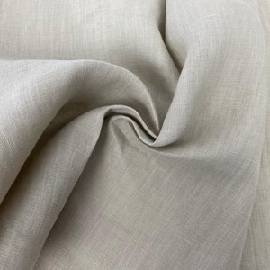 Può includere: Primo piano di un tessuto di lino beige con trama e pieghe visibili. Il tessuto ha un aspetto naturale, leggermente stropicciato, che suggerisce un materiale morbido e traspirante. Ideale per abbigliamento o arredamento.