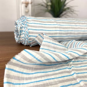 Può includere: Un rotolo di tessuto a righe bianche e blu. Il tessuto ha una trama di lino ed è perfetto per progetti di cucito.
