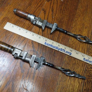 May include: Two custom-made metal bottle openers with wooden handles and twisted metal ends. The openers are next to a wooden ruler with the text "Kentucky811.org" and "Safety is in You".
