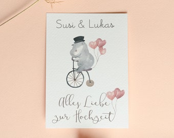 May include: A white card with a gray cartoon animal riding a bicycle with pink balloons and the text "Susi & Lukas" and "Alles Liebe zur Hochzeit".