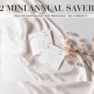 May include: Two white square paper cards featuring the text 12 MINI ANNUAL SAVERS, INSTANT DOWNLOAD, PDF PRINTABLE, NO CURRENCY. The cards display the months Dec and Jan, the year 2027, and weekly savings trackers with checkboxes.