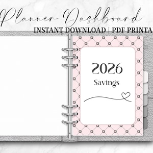 May include: A gray planner with the text "Planner Dashboard" and "Instant Download | PDF Printable". The planner is open to a page with "2026 Savings" on a pink patterned background. A heart graphic is also present.