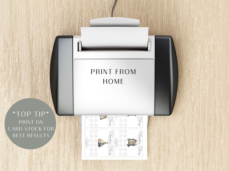 May include: A white and black printer with the text PRINT FROM HOME printed on the front. A sheet of paper with small printed graphics and circular icons is emerging from the bottom. A grey circular badge displays the text *TOP TIP* PRINT ON CARD STOCK FOR BEST RESULTS.