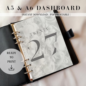 May include: A black ring-bound planner containing a dashboard page with a white floral background. The page features the text TWENTY 27 and IRIS in dark gray font. A circular badge on the left displays the text READY TO PRINT with a download icon.