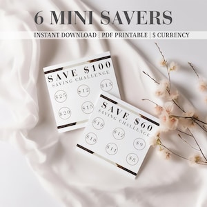 Peut inclure: Deux cartes carrées blanches avec du texte noir et des accents dorés métalliques. Une carte indique SAVE $100 SAVING CHALLENGE avec des cercles contenant $13, $12, $25, $15 et $20. L'autre indique SAVE $60 SAVING CHALLENGE avec des cercles contenant $10, $12, $9, $10, $11 et $8.