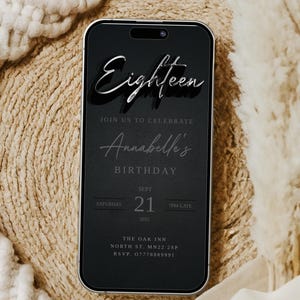 May include: A black smartphone screen shows a birthday invitation. The text reads "Eighteen" in a silver, 3D font, followed by "Join us to celebrate Annabelle's Birthday." The date is September 21, 2025. The invitation includes an address and RSVP details.