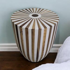 May include: A white and brown striped side table with a round top and a slightly flared base. The table has a sunburst design on the top.