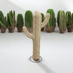 May include: A large, woven, beige cactus sculpture with a black metal stand. The cactus is surrounded by smaller, green cacti.