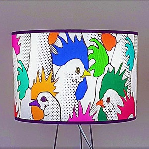 May include: A lampshade with a white background and a colorful pattern of roosters. The roosters are drawn in a cartoon style with bright colors, including blue, green, yellow, pink, and orange.
